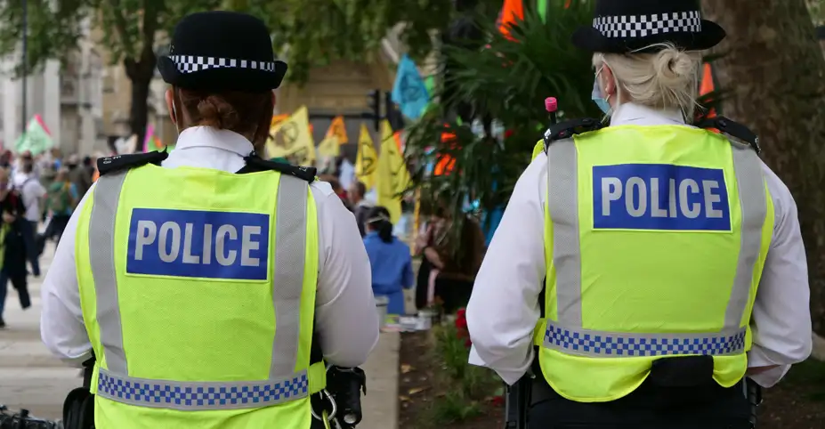 Two female police officers from behind, watching ongoing protest